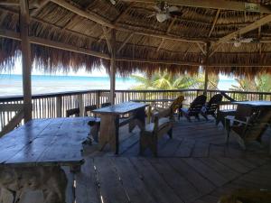 um deque de madeira com mesas e cadeiras na praia em Paradise Found em La Ceiba