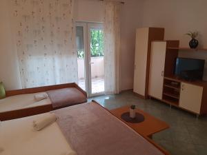 ein Wohnzimmer mit 2 Betten und einem TV in der Unterkunft Apartmani Leon in Šimuni