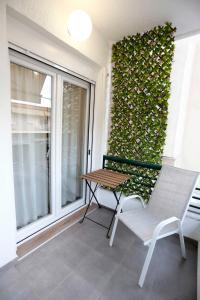 a chair and a table on a balcony with a ivy wall at Bianca Suites in Nea Moudania