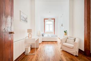 a white living room with a couch and a chair at Casa Portuguesa Fanqueiros in Lisbon