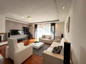 uma sala de estar com mobiliário branco e uma televisão em Apartmani Nova em Karlovac