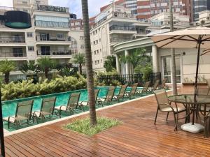 a deck with chairs and a table with an umbrella at Ap Menara - Perto do Hospital Albert Einstein e Estádio Morumbi in Sao Paulo