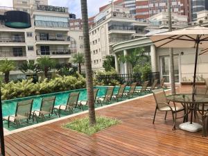 una terraza con sillas y una mesa con sombrilla en Apartamento Menara Morumbi, en São Paulo