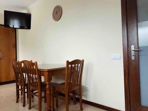 uma mesa de jantar com quatro cadeiras e um relógio na parede em Brazão Guest House em Santana