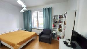 a bedroom with a bed and a chair and a television at Apartament blisko morza Kołobrzeg-Podczele in Kołobrzeg