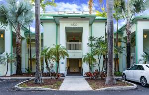 une voiture blanche garée devant un immeuble avec des palmiers dans l'établissement Modern Private Studio - King bed, Jacuzzi, Balcony and Pool, à Miami