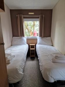 two beds in a small room with a window at The Bliss in Hastings
