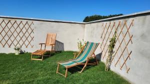 twee stoelen in het gras naast een muur bij Gîte de la Roulotte de l'Epine in Dallon