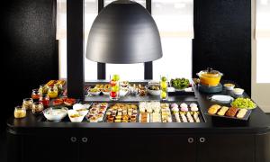 un buffet avec différents types de nourriture sur une table dans l'établissement The Originals City - Hotel Restaurant A Pic, à Cherbourg en Cotentin