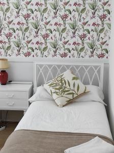 1 dormitorio con 1 cama y papel pintado con motivos florales en Acogedor piso de 3 habitaciones cerca del metro, en Getxo