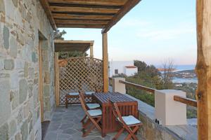 a patio with a table and chairs on a stone wall at Picollo Grecia Residence Panoramic View in Ermoupoli