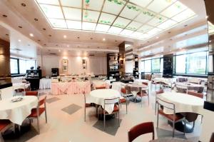 un ristorante con tavoli e sedie bianchi e un grande soffitto di New Tiffany's Park a Lido di Jesolo