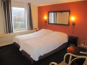 1 dormitorio con cama, espejo y ventana en Badhotel Zeecroft, en Wijk aan Zee