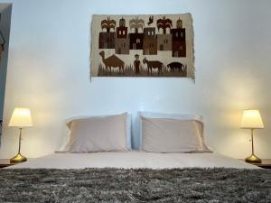 una camera da letto con un letto con due lampade e una foto a parete di Casa Às Oito ad Angra do Heroísmo
