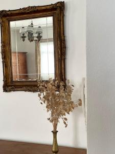 a vase with flowers in front of a mirror at Casa Às Oito in Angra do Heroísmo