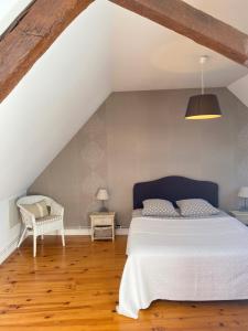 ein Schlafzimmer mit einem weißen Bett und einem Stuhl in der Unterkunft Le Clos Audy près de Chambord in Huisseau-sur-Cosson