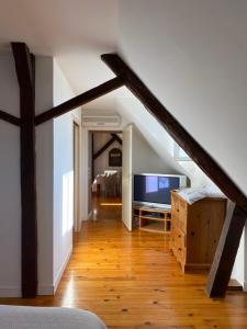 a living room with a staircase with a large television at Le Clos Audy près de Chambord in Huisseau-sur-Cosson