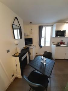 Habitación pequeña con mesa, sillas y cocina. en Studio équipé métro Abbesses à Montmartre, en París