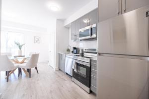 a kitchen with a refrigerator and a table with chairs at Luxury & Comfy Apartment, Mins Drive To All Niagara Falls Attraction in Niagara Falls