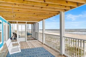un porche con un columpio y la playa en The Blue Whale en Gulf Shores
