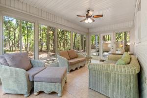 a screened in porch with chairs and a ceiling fan at Island House in Dauphin Island