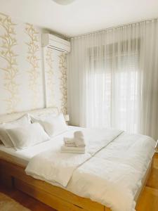 a bedroom with a white bed with a book on it at Aurora Apartment in Podgorica