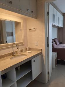 un bagno con lavandino, specchio e letto di Apartamento Top Praça da Bandeira - Praia do Forte a Cabo Frio Altre 32 foto