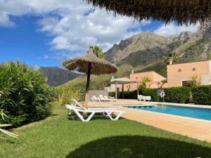 a resort with a pool and a umbrella and chairs at Casa Abeja in Colonia de Sant Pere