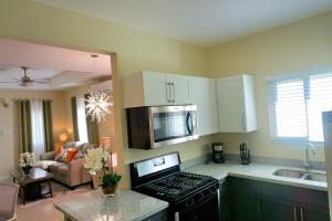 a kitchen with a stove top oven next to a living room at Paradise Oasis at Oceanpointe - pool and free parking in Lucea