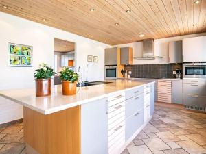 Hurupにある12 person holiday home in Hurup Thyの白いキャビネットと木製の天井が備わるキッチン
