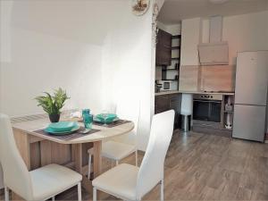 una cucina con un tavolo di legno e sedie bianche di Szellőrózsa Apartman a Fonyód