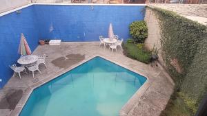 una piscina con mesas y sillas junto a una pared azul en Pool Party House, en Guatemala