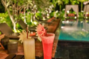 dos cócteles sentados en una mesa junto a una piscina en Home Indochine D'angkor Hotel, en Siem Reap