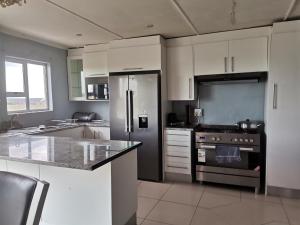 a kitchen with white cabinets and a stainless steel refrigerator at Village Stay Ngcamngeni in Debe Nek