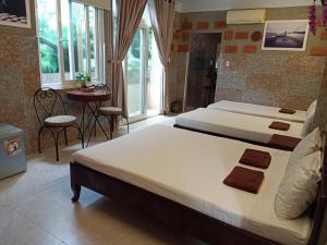 a bedroom with two beds and a table and windows at Terra Cotta Homestay in Hoi An