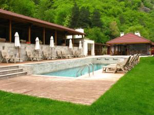 a pool with chairs and umbrellas next to a house at Хотел Аква Варвара in Varvara