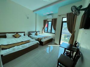 a bedroom with two beds and a desk and a window at Thái Tâm MOTEL in Dồng Văn