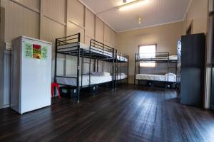 a room with three bunk beds and a refrigerator at The Jack Backpackers in Cairns
