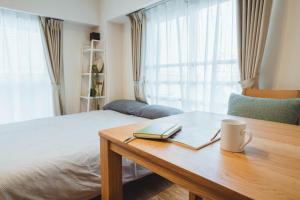 a bedroom with a table with a laptop and a book at City Hideout in Tokyo