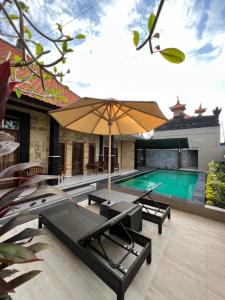 a swimming pool with chairs and an umbrella at Nari Homestay in Canggu