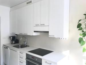 una cocina blanca con fregadero y armarios blancos en Avara keskusta asunto + oma ilmainen parkkipaikka en Tampere