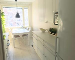 a kitchen with white cabinets and a table and a window at Avara keskusta asunto + oma ilmainen parkkipaikka in Tampere