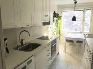 uma cozinha com armários brancos, um lavatório e uma janela em Avara keskusta asunto + oma ilmainen parkkipaikka em Tampere