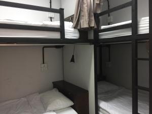 two bunk beds in a dorm room with white sheets at Backpack Station in Bangkok