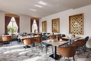 a restaurant with tables and chairs and windows at Hotel Das Bischof in Tauberbischofsheim