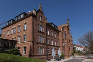 ein großes Backsteingebäude mit Sonnenschirmen davor in der Unterkunft Hotel Das Bischof in Tauberbischofsheim