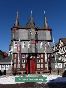 ein Gebäude mit einem schwarzen Dach und einer roten Tür in der Unterkunft Tiny Apartment in Gemünden an der Wohra in Gemünden an der Wohra