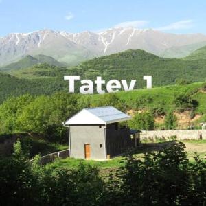 a small building on a hill with mountains in the background at Tatev 1 in Tatʼev