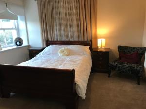 The Glen Mona Hotel في Maughold: غرفة نوم مع سرير مع كلب أبيض يستلقي عليها
