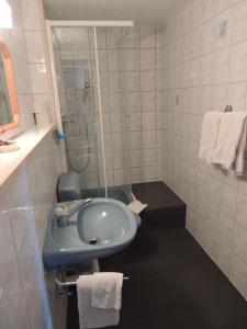 a bathroom with a sink and a shower with towels at Hotel de la Gare in Cousset 